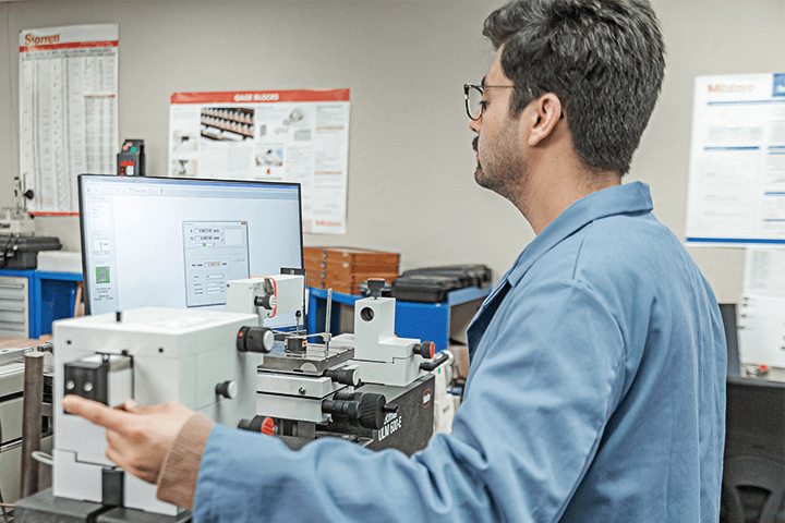 Probata employee in a blue lab coat running equipment tests on a computer