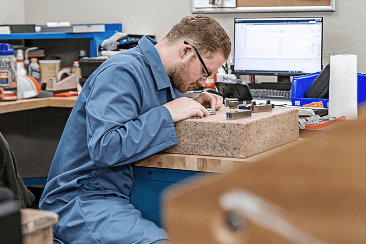 Probata employee in a blue lab coat intently focusing on equipment measurements