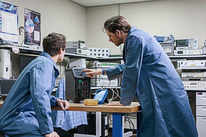 Probata employees in blue lab coats looking at equipment