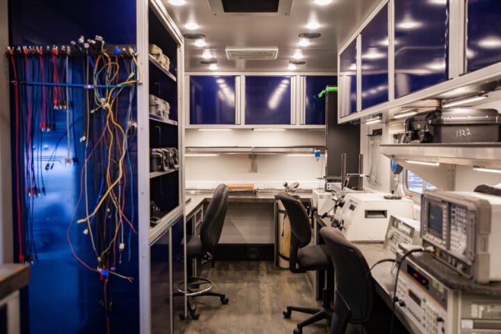Inside view of the Probata Mobile calibration station. A rectangular room with chairs, desks, testing equipment, and organized cables.