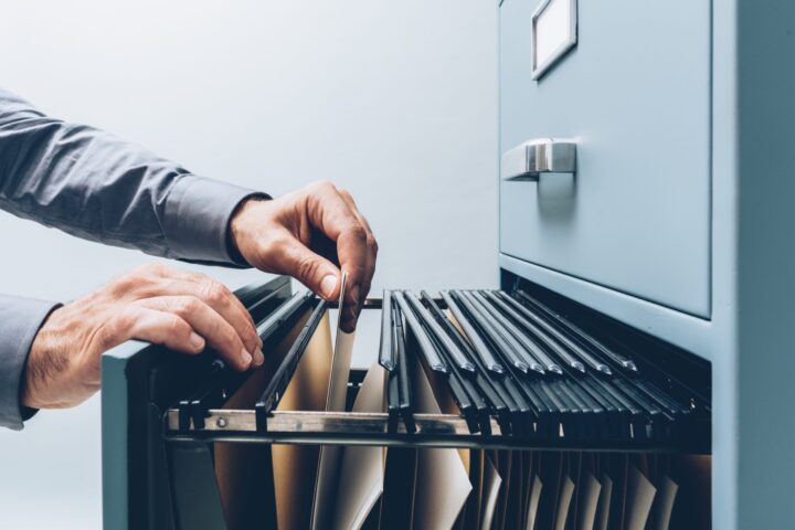 Male hands looking through gray filing cabinet