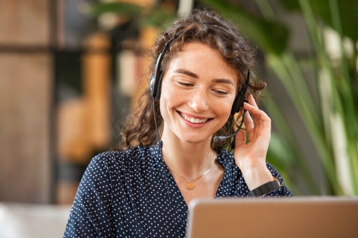 Lady smiling with a headset on at the computer