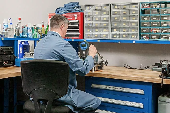 Probata employee in blue lab coat looking at testing equipment
