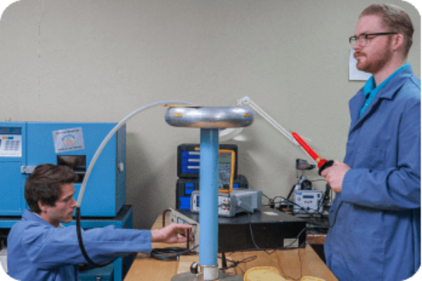 2 probata employees in blue lab coats testing electric tests around a tesla coil